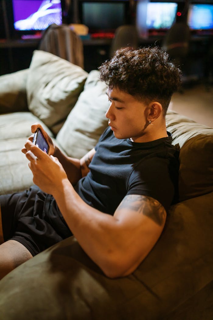 A young man intensely focused on gaming indoors with his smartphone.